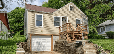 Cozy home with wooden deck and stone accents nestled in a leafy residential neighborhood.