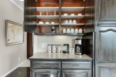 Your morning ritual awaits in this elegant coffee station, with premium appliances and organized dishes ready for your perfect cup.
