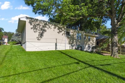Modern property nestled on a spacious lawn beneath mature shade trees in a peaceful residential neighborhood setting.