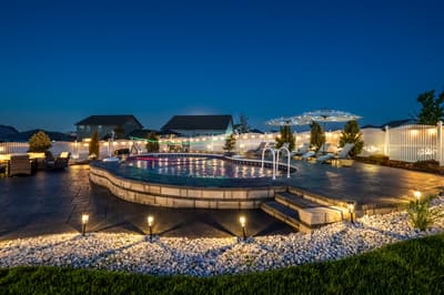 Stunning illuminated pool area with elegant stone features and ambient lighting creating a magical evening atmosphere.