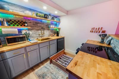 Whip up culinary masterpieces in your vibrant kitchen featuring butcher block counters, colorful LED backlighting, and thoughtfully organized storage.