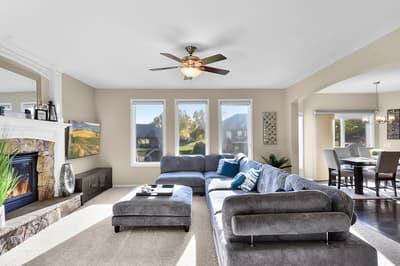 Unwind in your spacious living room featuring a cozy stone fireplace, plush sectional sofa, and scenic mountain views through bright windows.