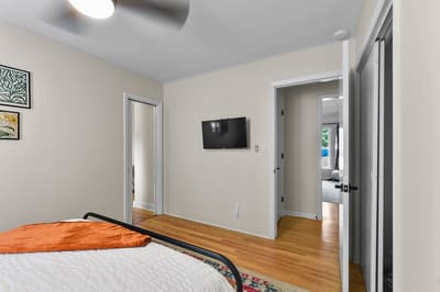 Your bright bedroom features warm hardwood floors, a wall-mounted TV for your evening entertainment, and modern art that adds character to your peaceful retreat.