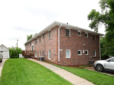 Two-story brick building set in a quiet residential neighborhood with mature trees and well-maintained lawn.