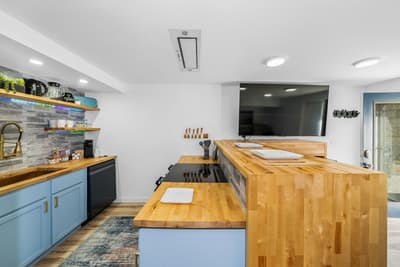Step into your modern kitchen featuring warm butcher block counters, sleek blue cabinetry, and everything you need to create memorable meals.