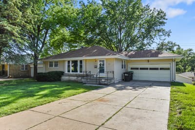 Charming single-story home sits nestled among mature trees in a peaceful residential neighborhood with convenient driveway parking.