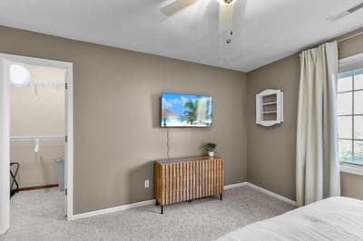 Unwind in your spacious bedroom featuring a wall-mounted TV and stylish wood credenza, with an en-suite bathroom for added convenience.