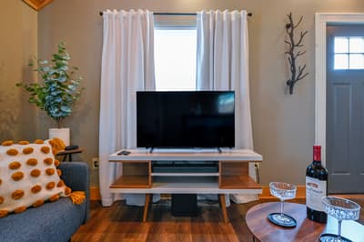 Unwind in your cozy living room where modern comfort meets rustic charm, complete with entertainment and wine for perfect evenings.