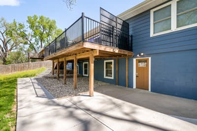 Modern blue exterior with upper deck, covered parking, and private entrance in a quiet residential setting.