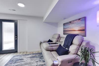 Sink into plush recliners in your entertainment space, where purple mood lighting and sunset artwork create the perfect ambiance for movie nights.