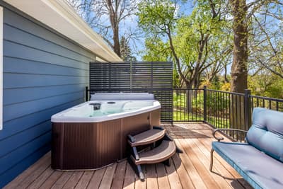 Soak in your private hot tub on this spacious deck, surrounded by mature trees and comfortable seating for ultimate relaxation.