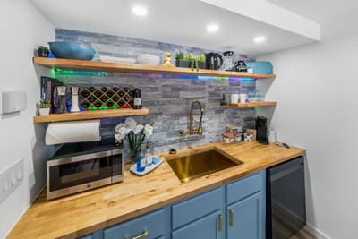 Your stylish kitchenette features warm wood countertops, blue cabinetry, and floating shelves—perfect for preparing meals during your stay.