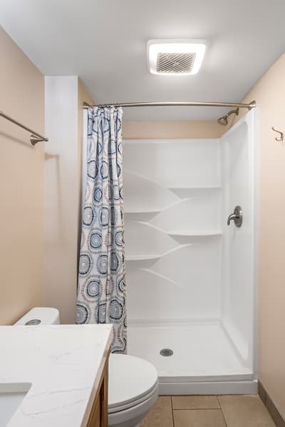 Step into your private bathroom featuring a spacious walk-in shower with stylish patterned curtain and modern fixtures for a refreshing start to your day.