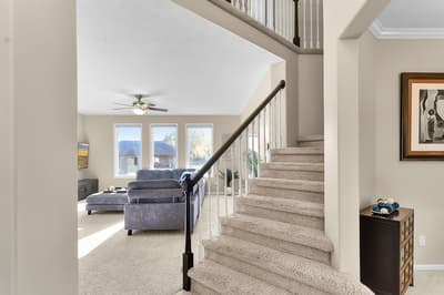 Settle into your spacious living room with plush seating and natural light streaming through large windows, while the elegant staircase adds charm to your home.