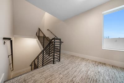 Your cozy upstairs retreat features modern railings and soft carpeting, with natural light streaming through the window to brighten your peaceful space.