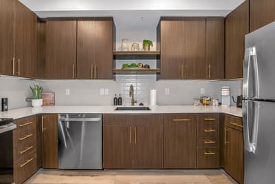 Step into your fully equipped kitchen featuring sleek wood cabinetry, stainless steel appliances, and pristine countertops perfect for preparing memorable meals.