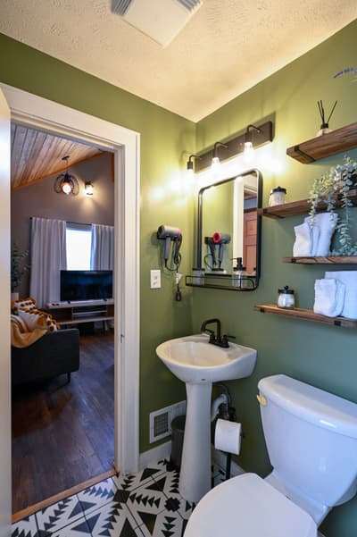 Freshen up in your stylish green bathroom with modern amenities and fluffy towels waiting on rustic shelves.