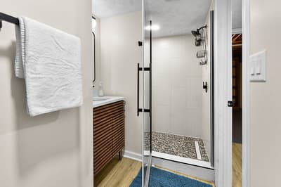 Refresh in your sleek bathroom with modern glass shower, plush towels, and stylish wood vanity.