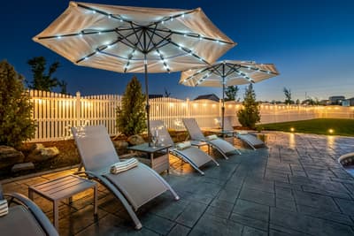 Unwind on your private patio where illuminated umbrellas cast a warm glow over plush loungers, creating the perfect evening retreat.