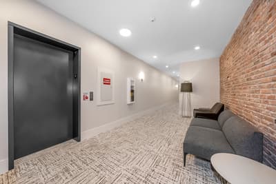 Step into your stylish hallway featuring warm brick walls and modern comfort - your peaceful retreat awaits just steps away.