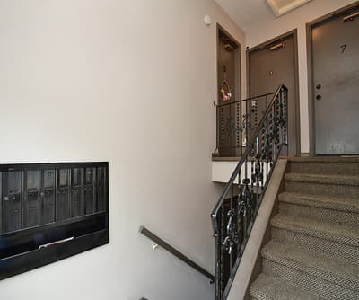 The property entrance features a well-maintained stairwell with ornate ironwork railing leading to numbered apartment doors, offering secure access in a clean, quiet building.