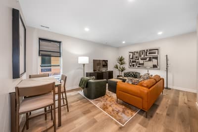 Settle into your stylish open-plan living space with plush leather seating, modern dining area, and warm wood floors that invite barefoot relaxation.